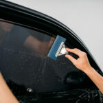 Male specialist with drier, car tinting film installation process, tinted auto glass installing procedure